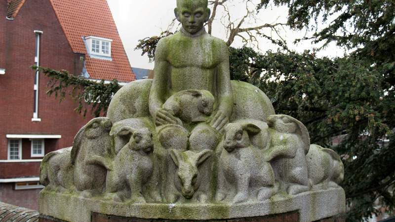 Stone figures of a child with rabbits by Hildo Krop